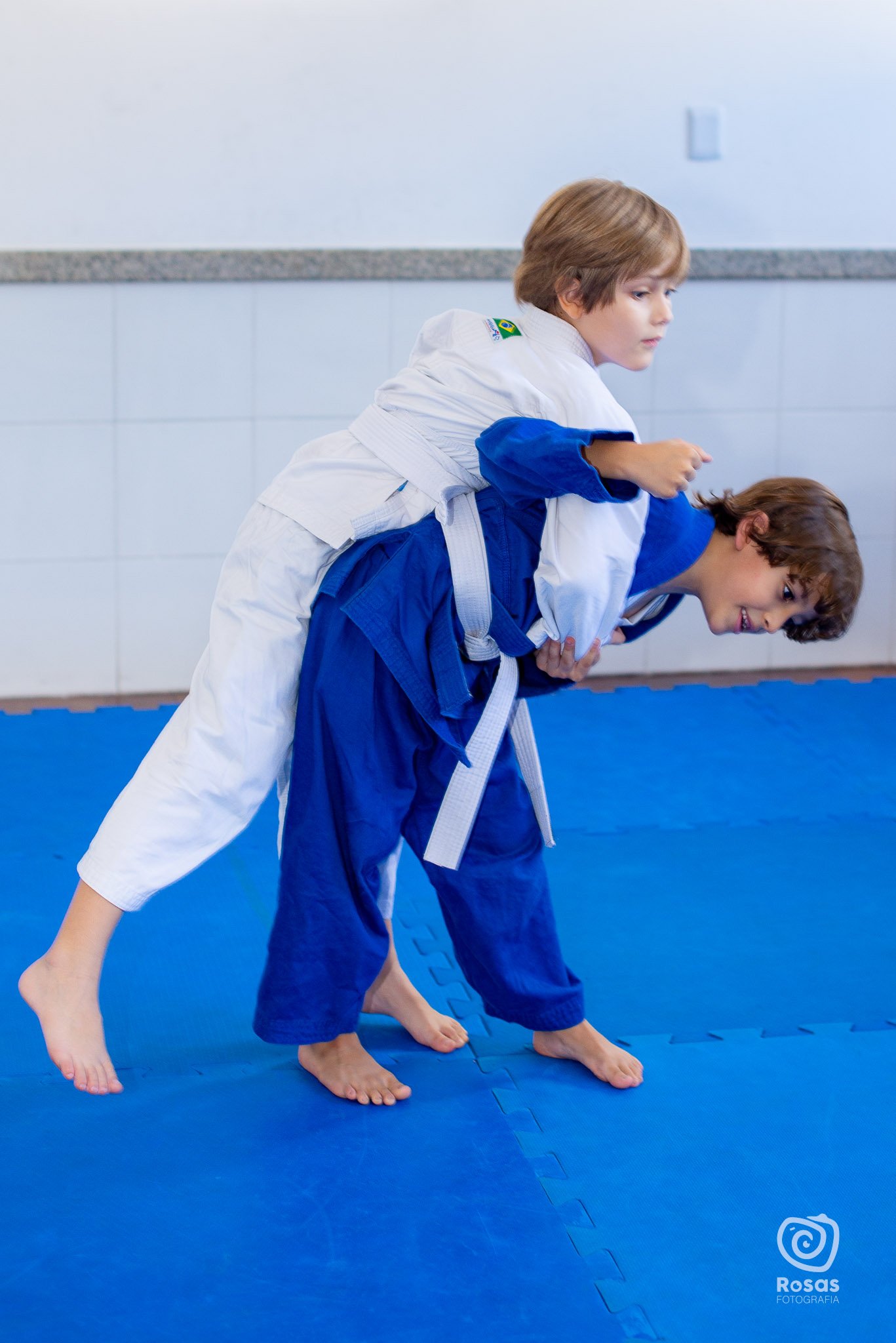 Alunos treinando queda em aula de judô no tatame da escola