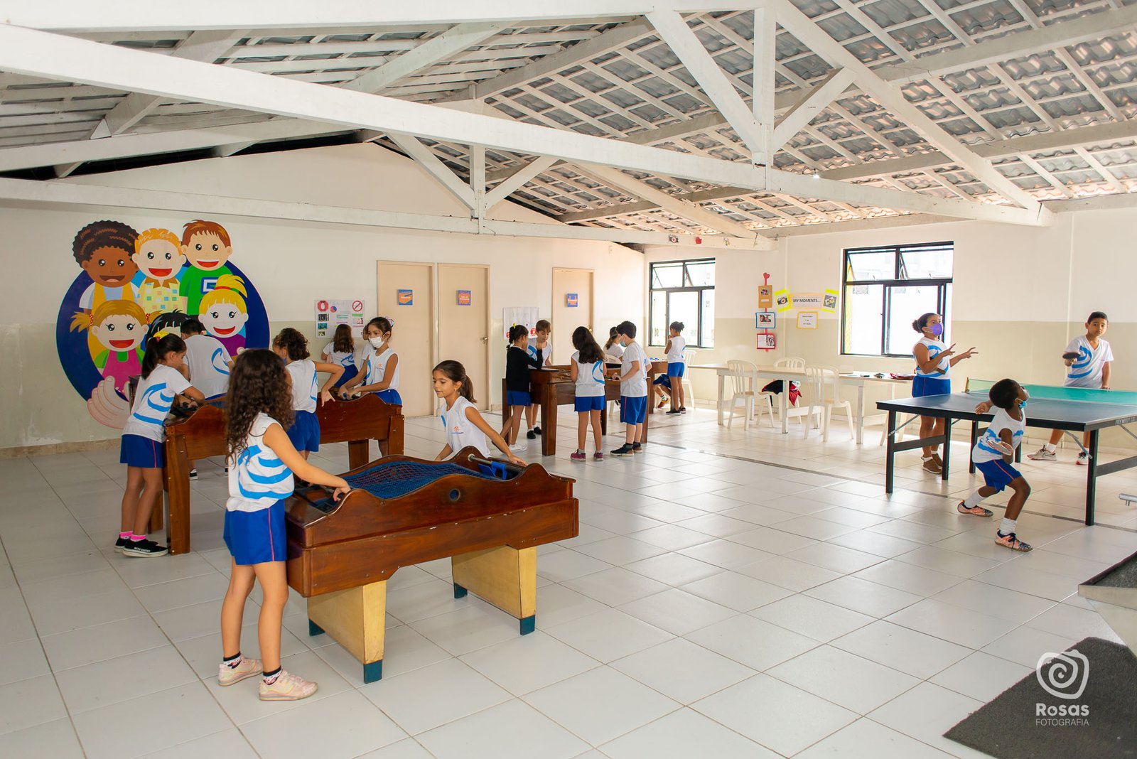 Estudantes do turno integral jogando tênis de mesa e pebolim no salão da escola