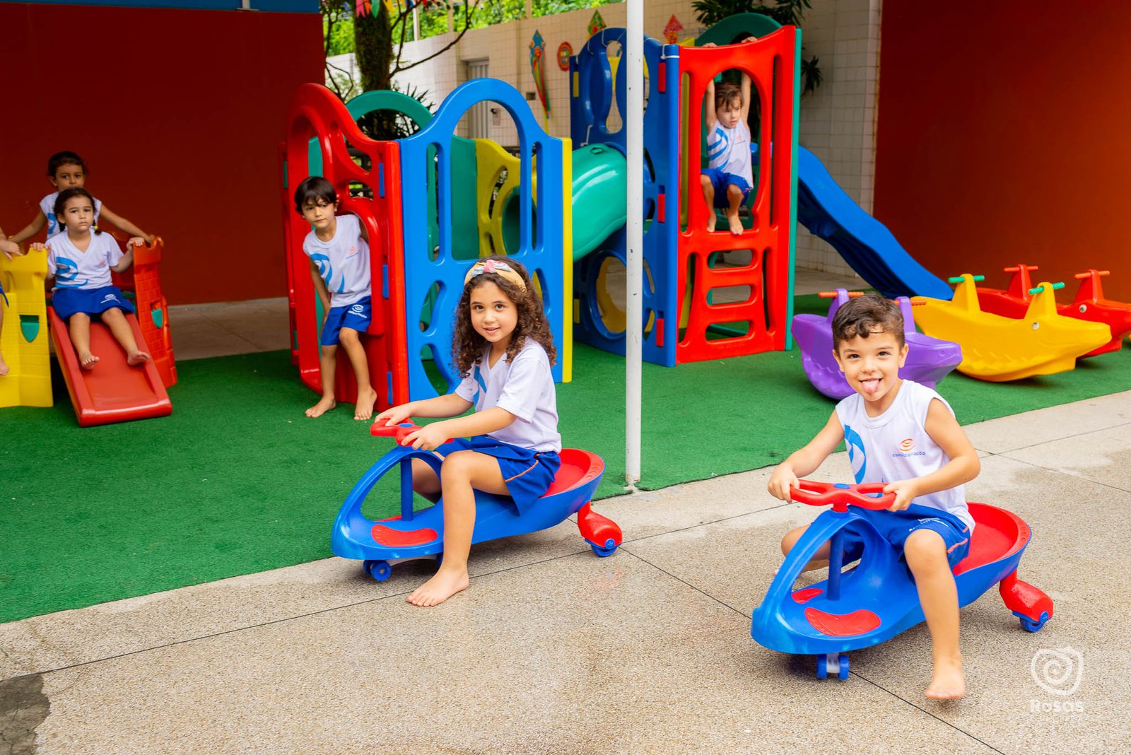 Crianças no escorregador e nos brinquedos do parquinho da escola