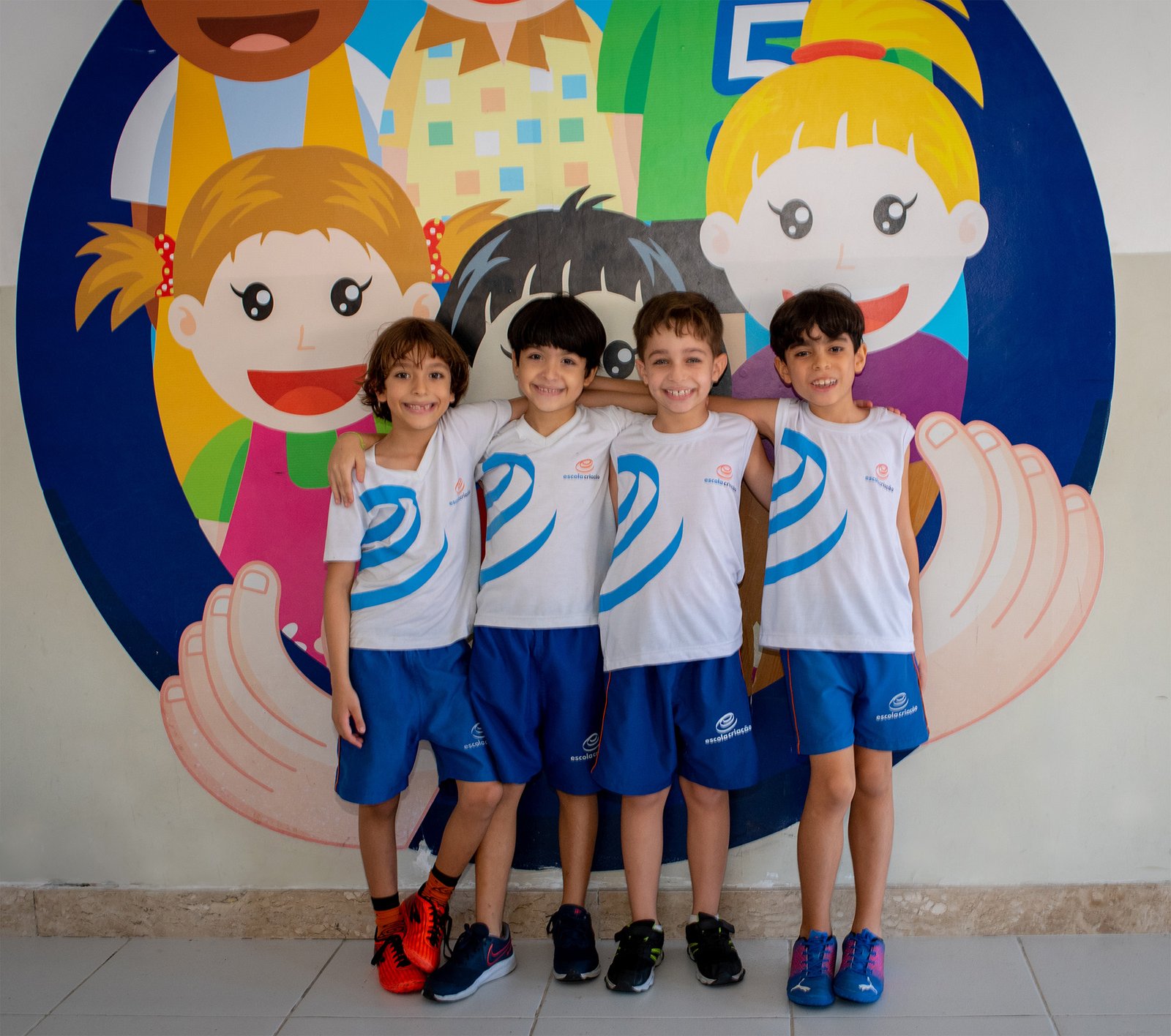 Estudantes posando diante do mural colorido da escola